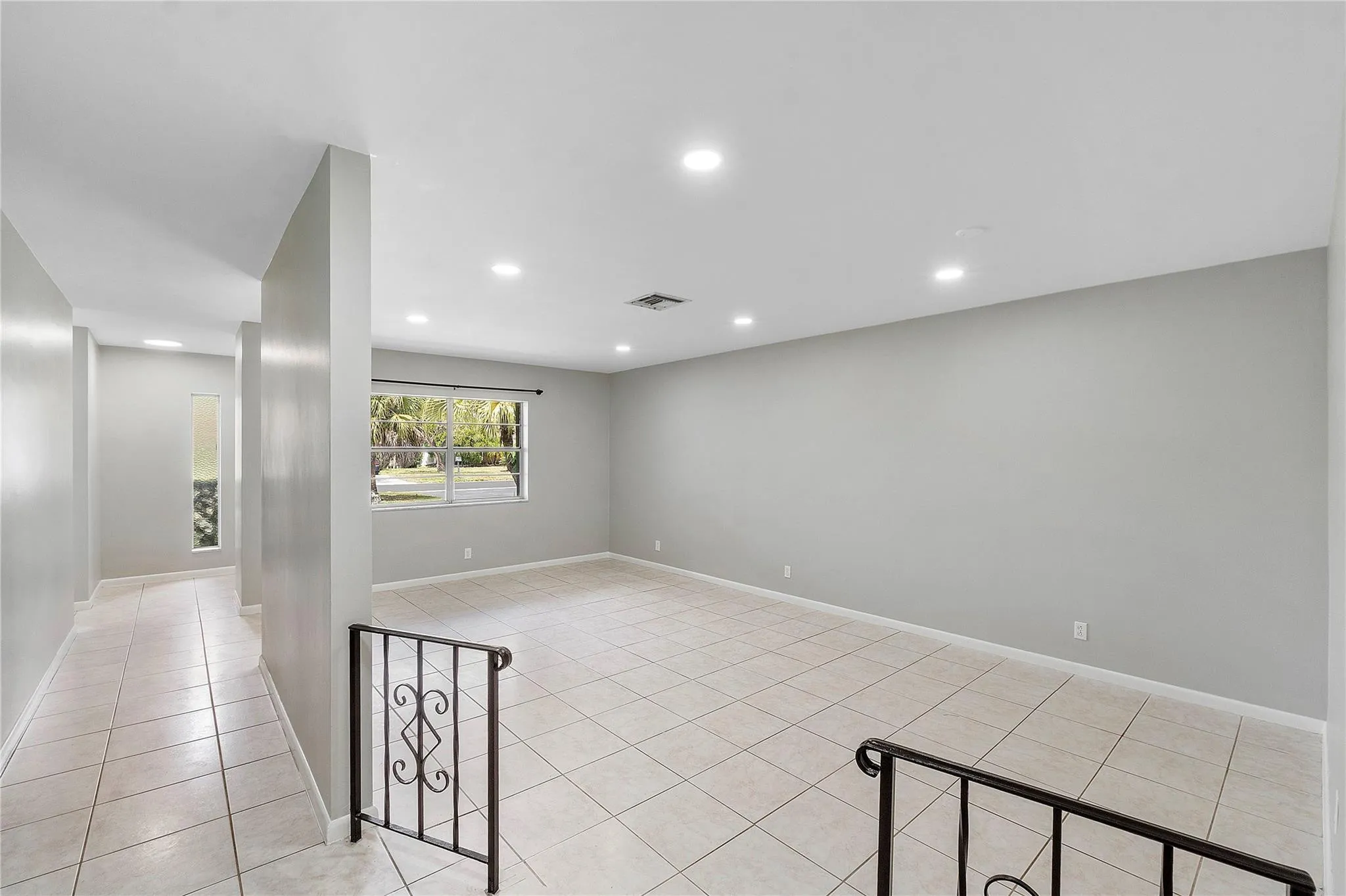 Open-concept living area featuring neutral-toned walls, recessed lighting, and large format tile flooring