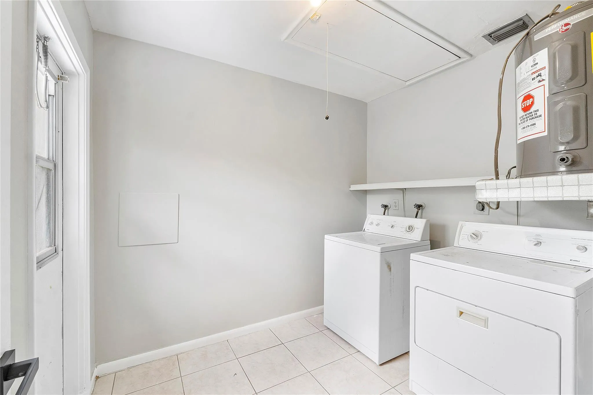 Dedicated laundry area featuring a water heater, tile flooring, and light gray walls