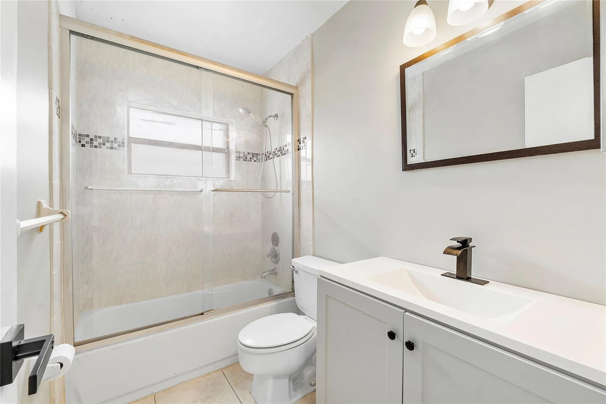 Bathroom featuring a white vanity with integrated sink, bronze faucet, and framed mirror