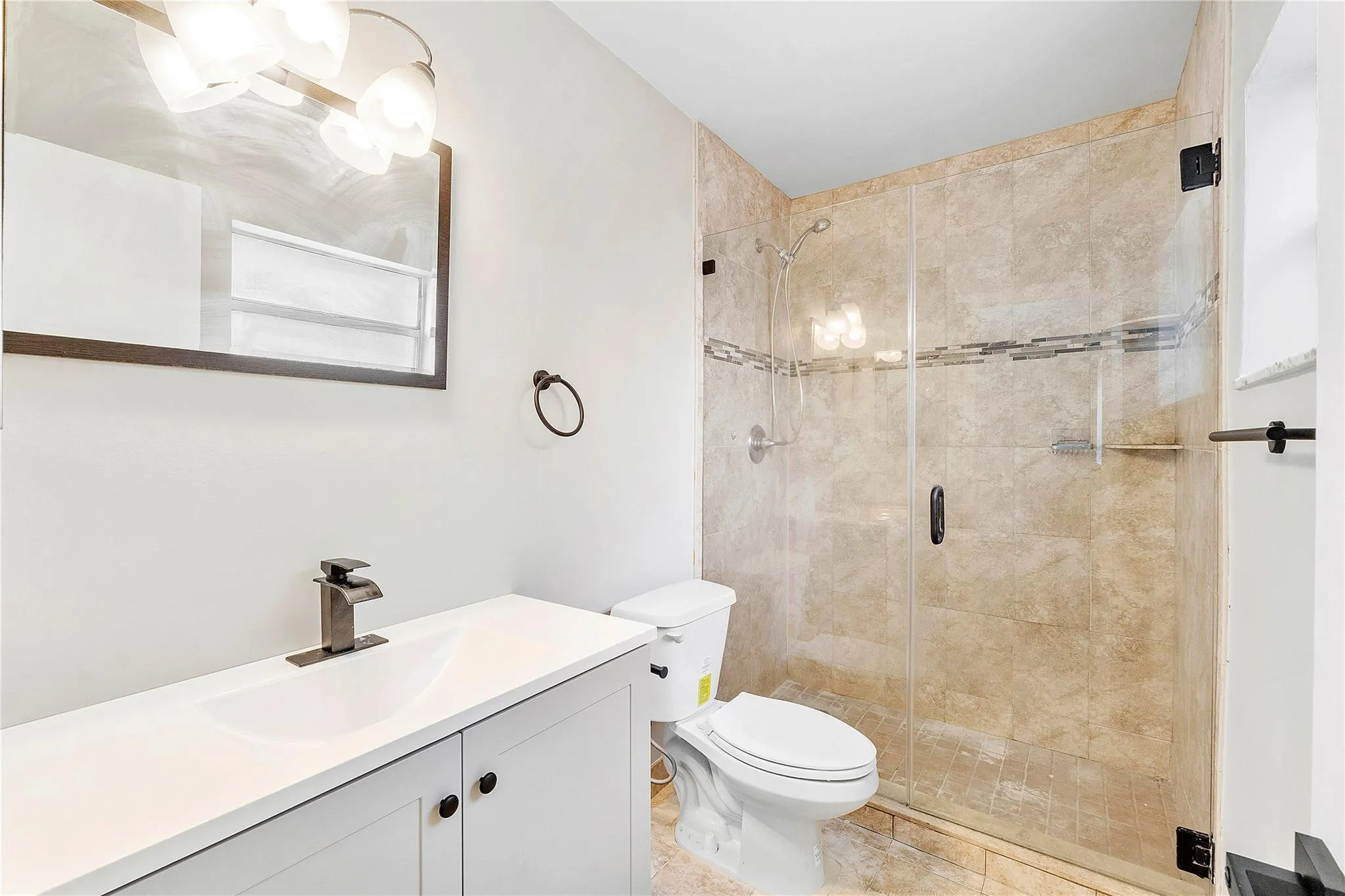 Bathroom featuring a clear glass shower enclosure with tiled walls and an accent band