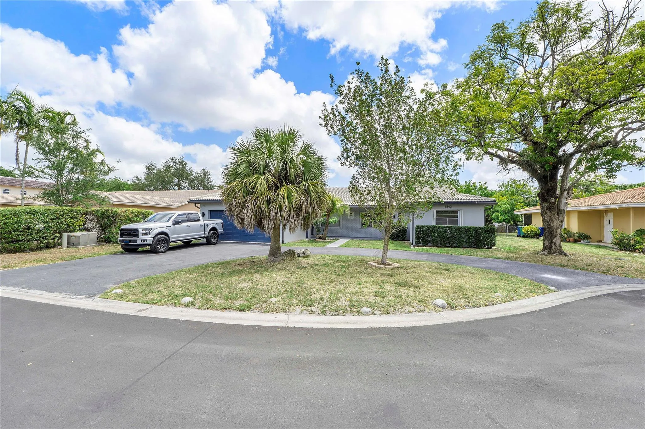1/2 Duplex (w/o Garage) Single-story residence featuring a gray exterior, blue garage door, and a paved driveway