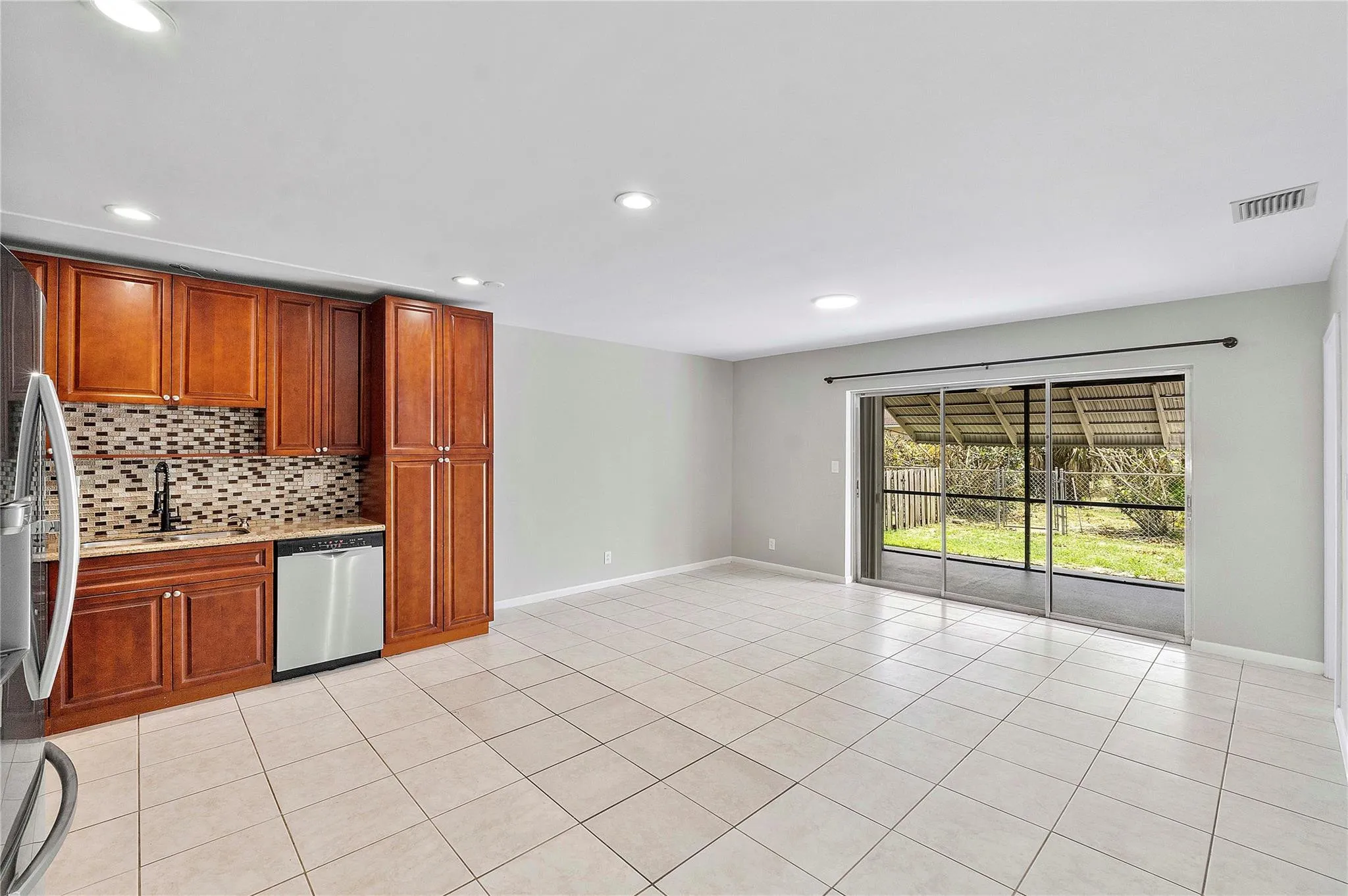 Open-concept living area featuring light-toned tile flooring, recessed lighting, and a neutral wall palette