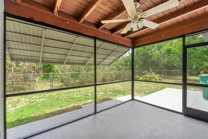 Screened porch featuring a textured concrete floor, a wood plank ceiling, and a ceiling fan