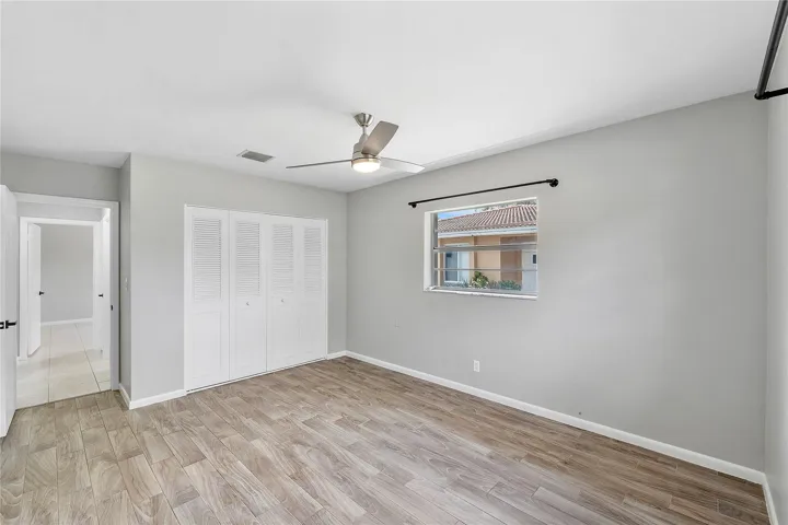 Spacious room featuring wood-finish flooring, light grey walls, and a contemporary ceiling fan