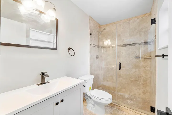 Bathroom featuring a clear glass shower enclosure with tiled walls and an accent band