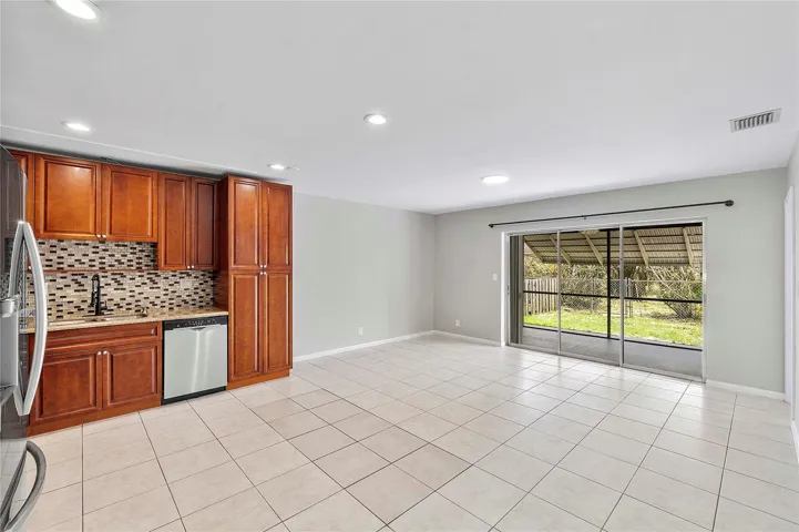 Open-concept living area featuring light-toned tile flooring, recessed lighting, and a neutral wall palette