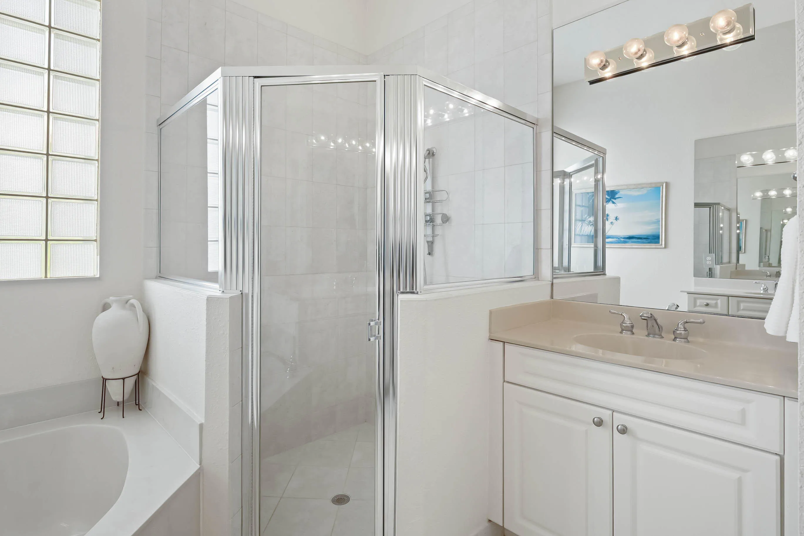 Bathroom featuring a glass-enclosed shower, built-in bathtub, glass block window, vanity with an integrated sink, and a wall-mounted light fixture