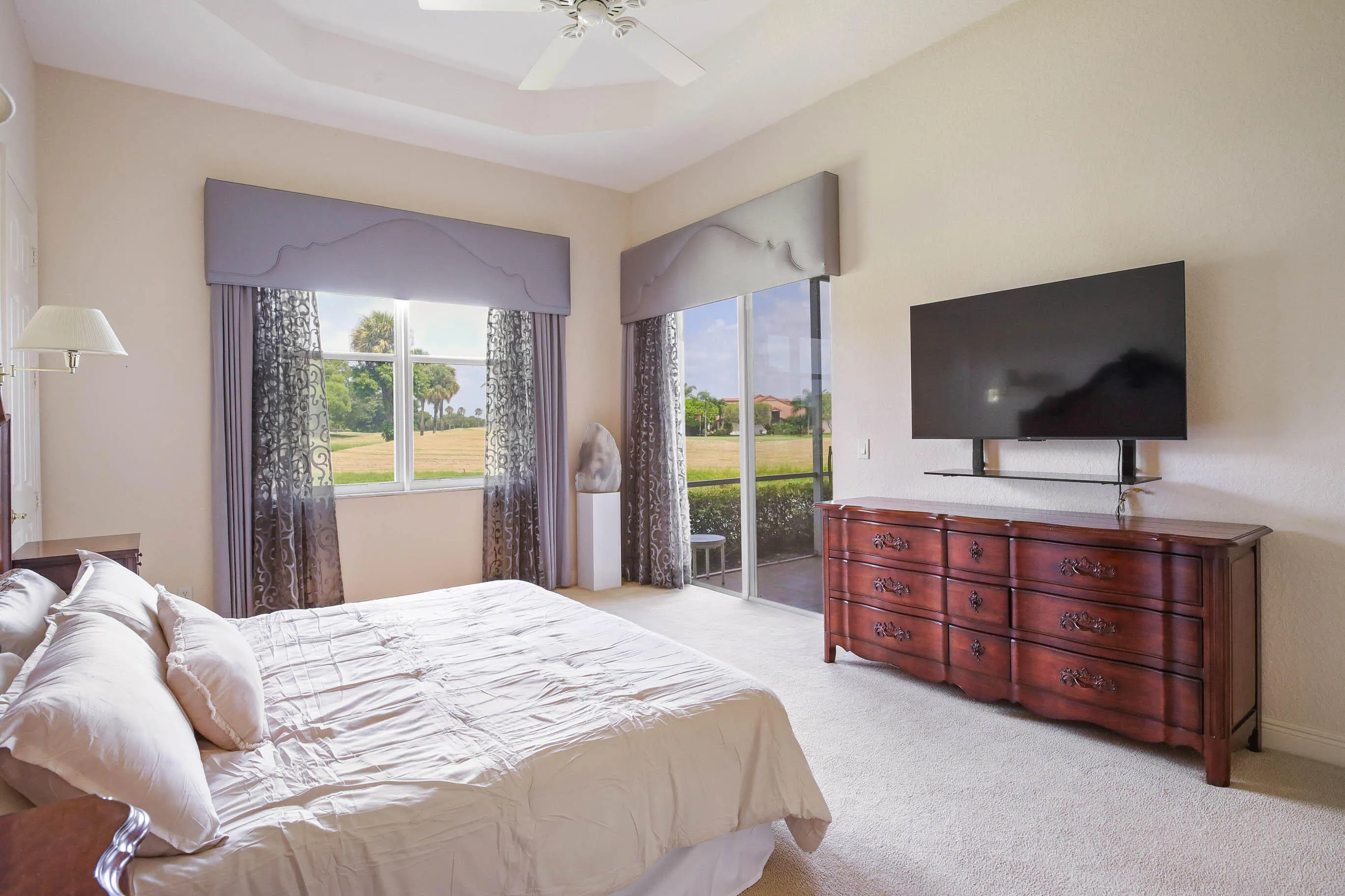 Bedroom featuring a tray ceiling with a ceiling fan, wall-mounted sconces , and carpet flooring