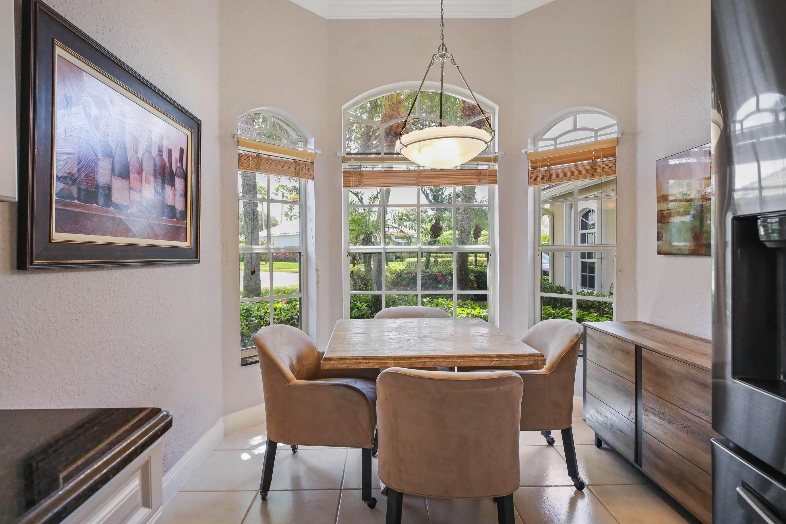 Breakfast nook featuring a bay window with arched transoms, crown molding, a hanging pendant light, and tile flooring