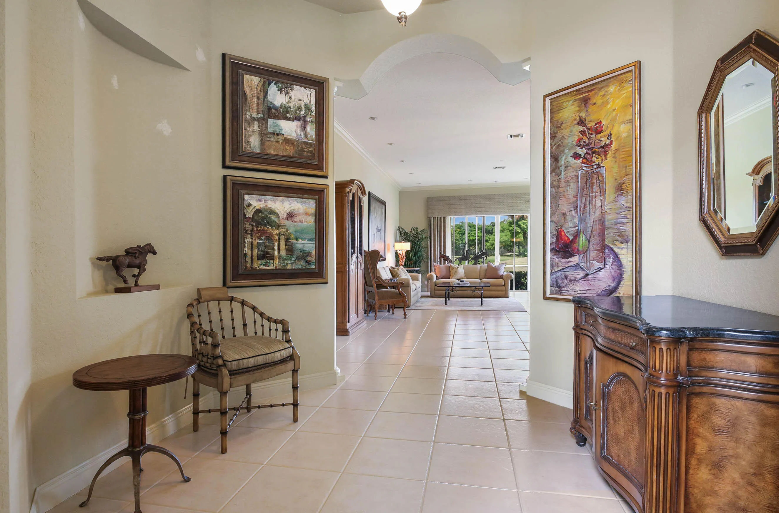 Expansive hallway featuring neutral tile flooring, an arched entryway, and a built-in wall niche