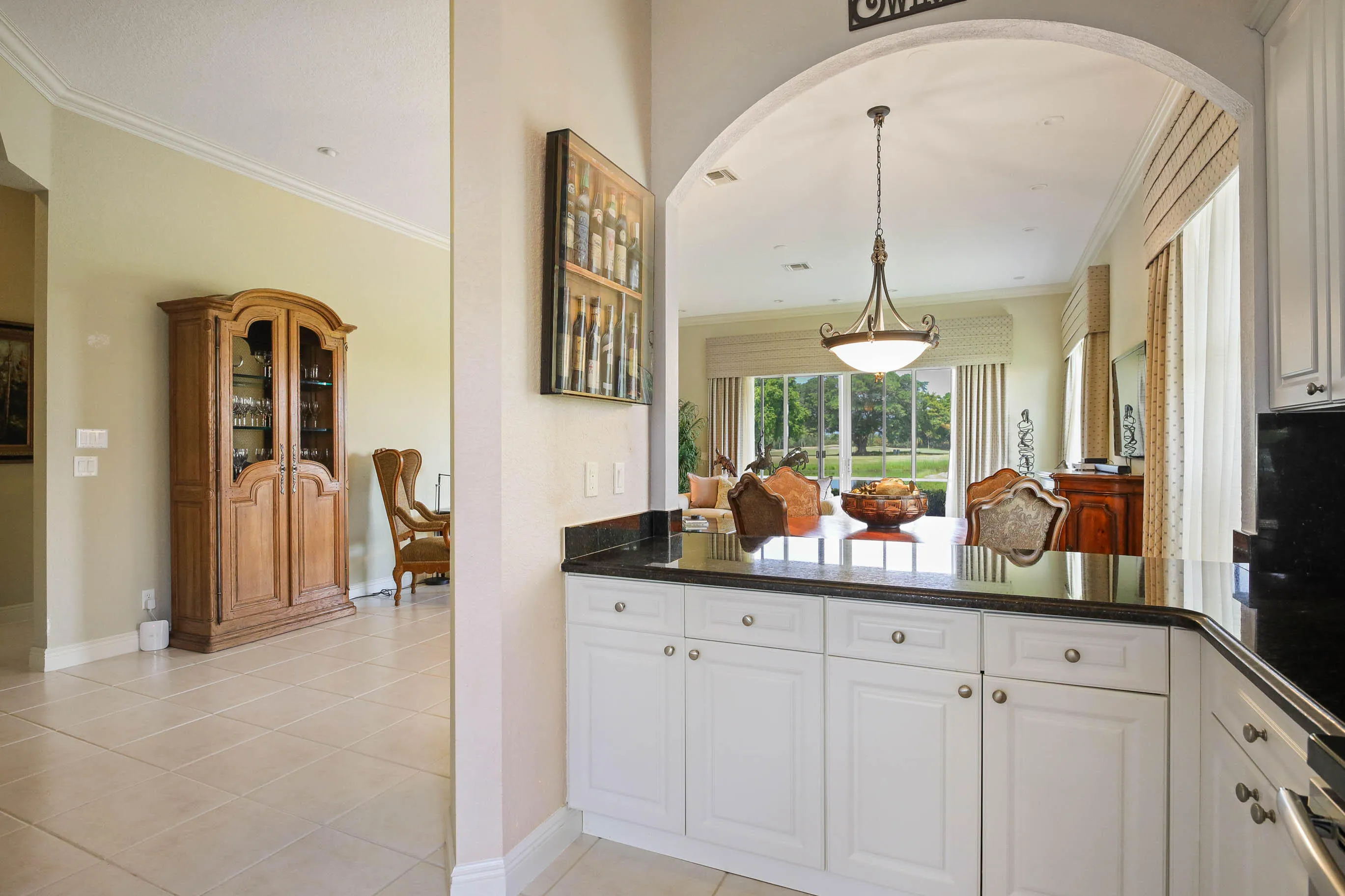 Kitchen pass-through featuring white cabinetry, and dark stone countertop