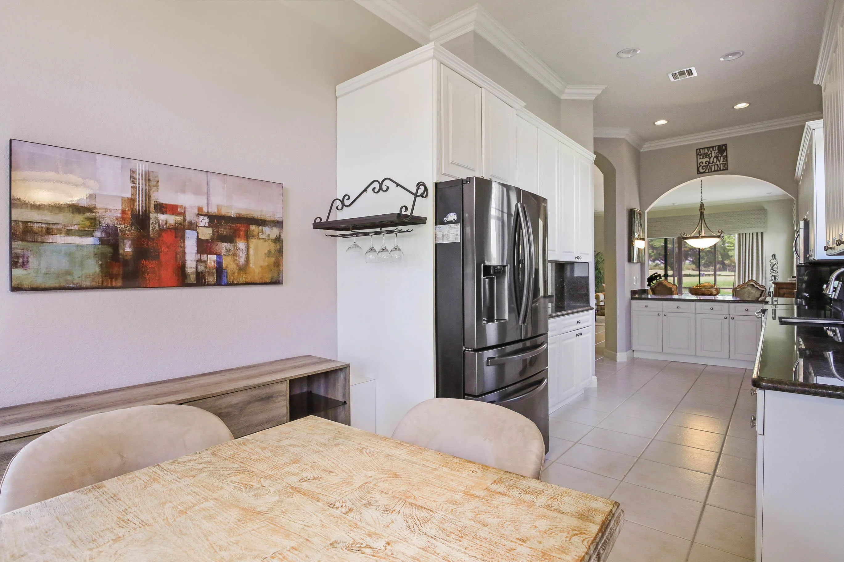 Kitchen with white cabinetry, stainless steel refrigerator, dark countertops, and tile flooring
