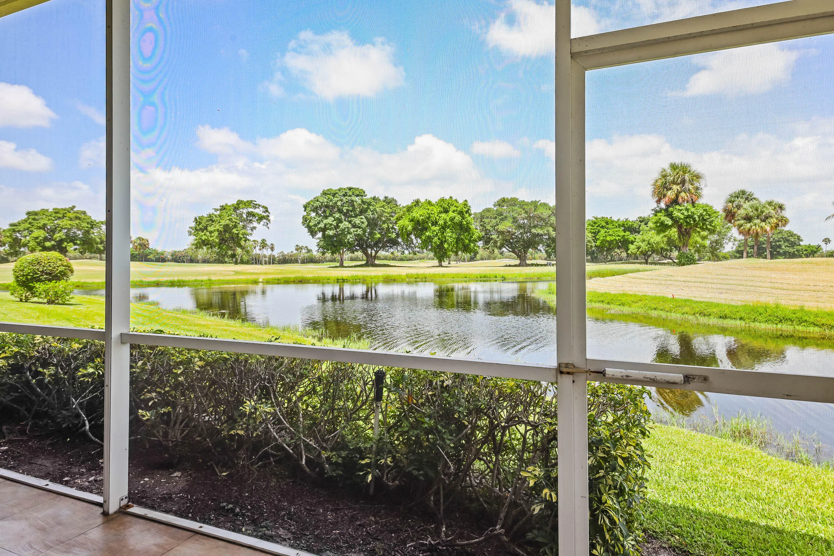 Screened patio offering expansive water frontage with natural landscaping and distant foliage