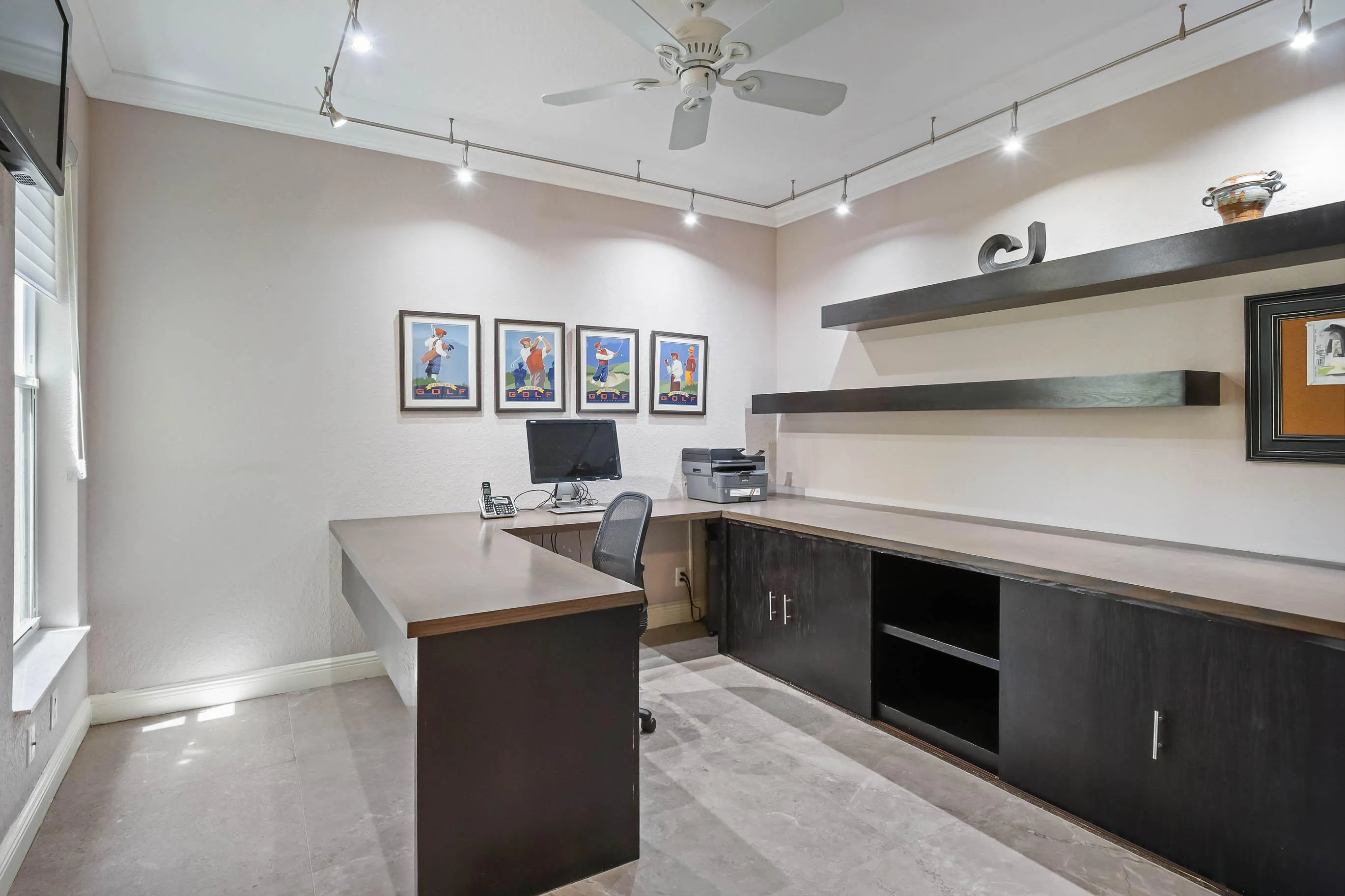 Dedicated workspace featuring extensive built-in cabinetry, floating shelves, and a ceiling fan