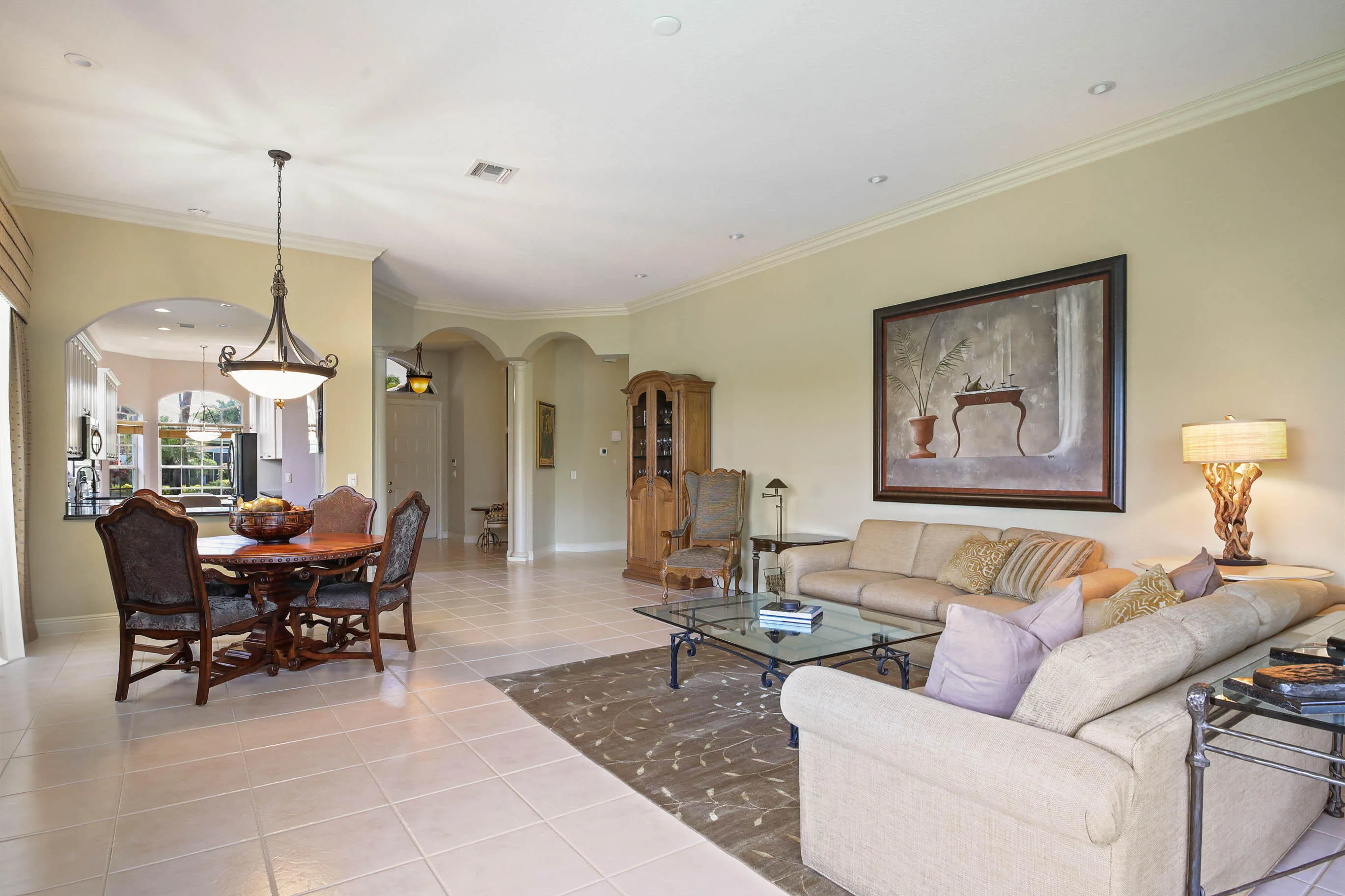 Open concept living area with light-toned tile flooring, recessed lighting, and crown molding