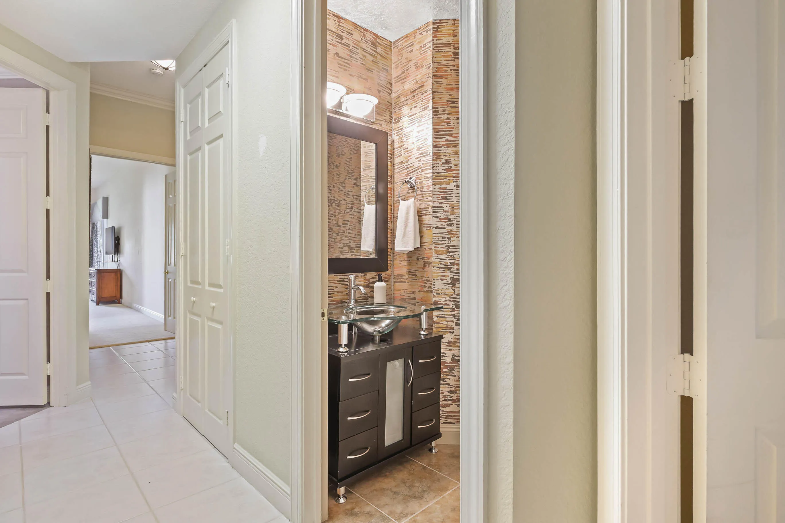 Powder room featuring a stacked stone accent wall, dark wood-finish vanity with drawer storage, vessel sink, and wall-mounted mirror