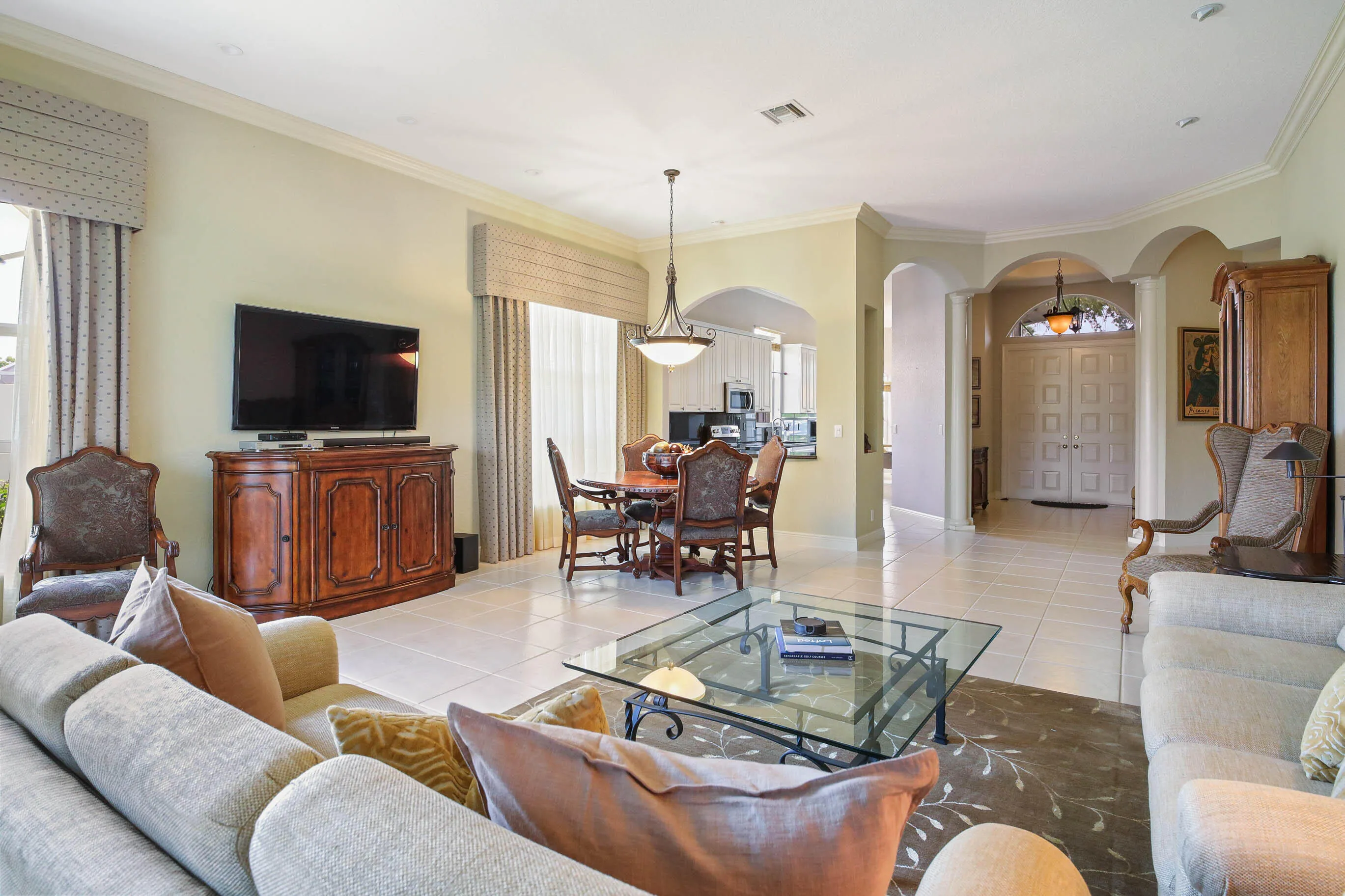 Spacious living area featuring light-toned tile flooring, recessed lighting, and crown molding