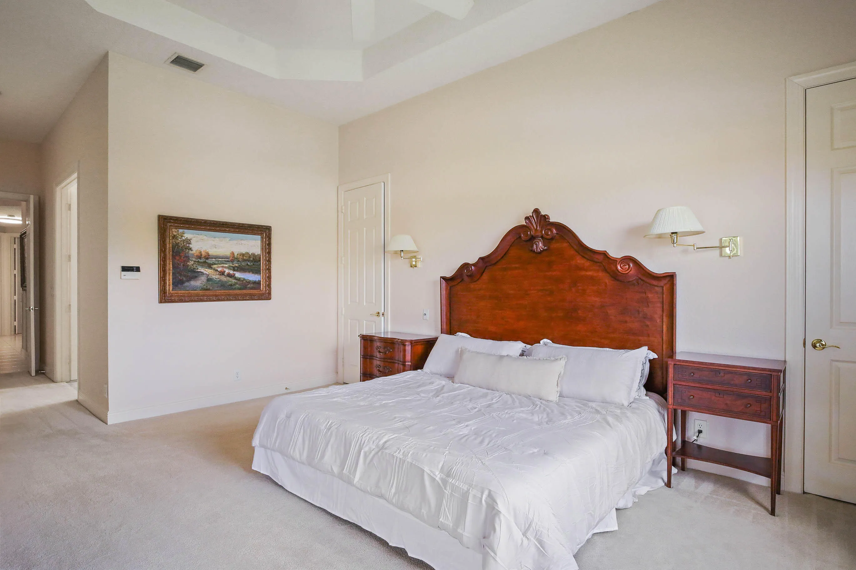 Spacious room featuring a tray ceiling, light-toned carpeting, and wall-mounted sconces