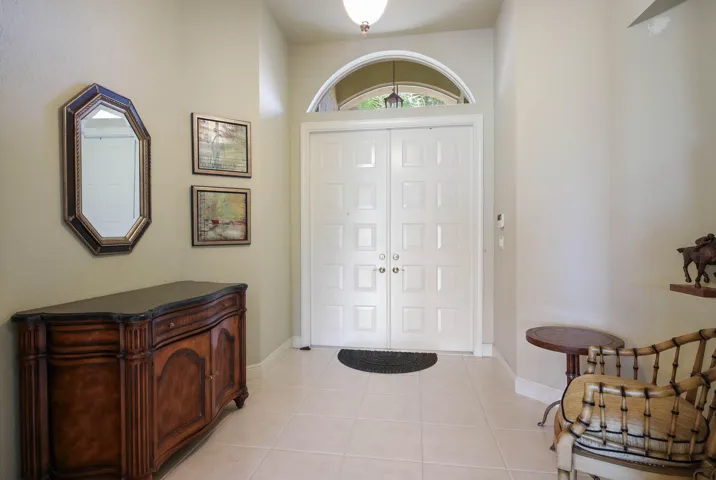 Double-door entry with arched transom window, tiled flooring, and an overhead light fixture
