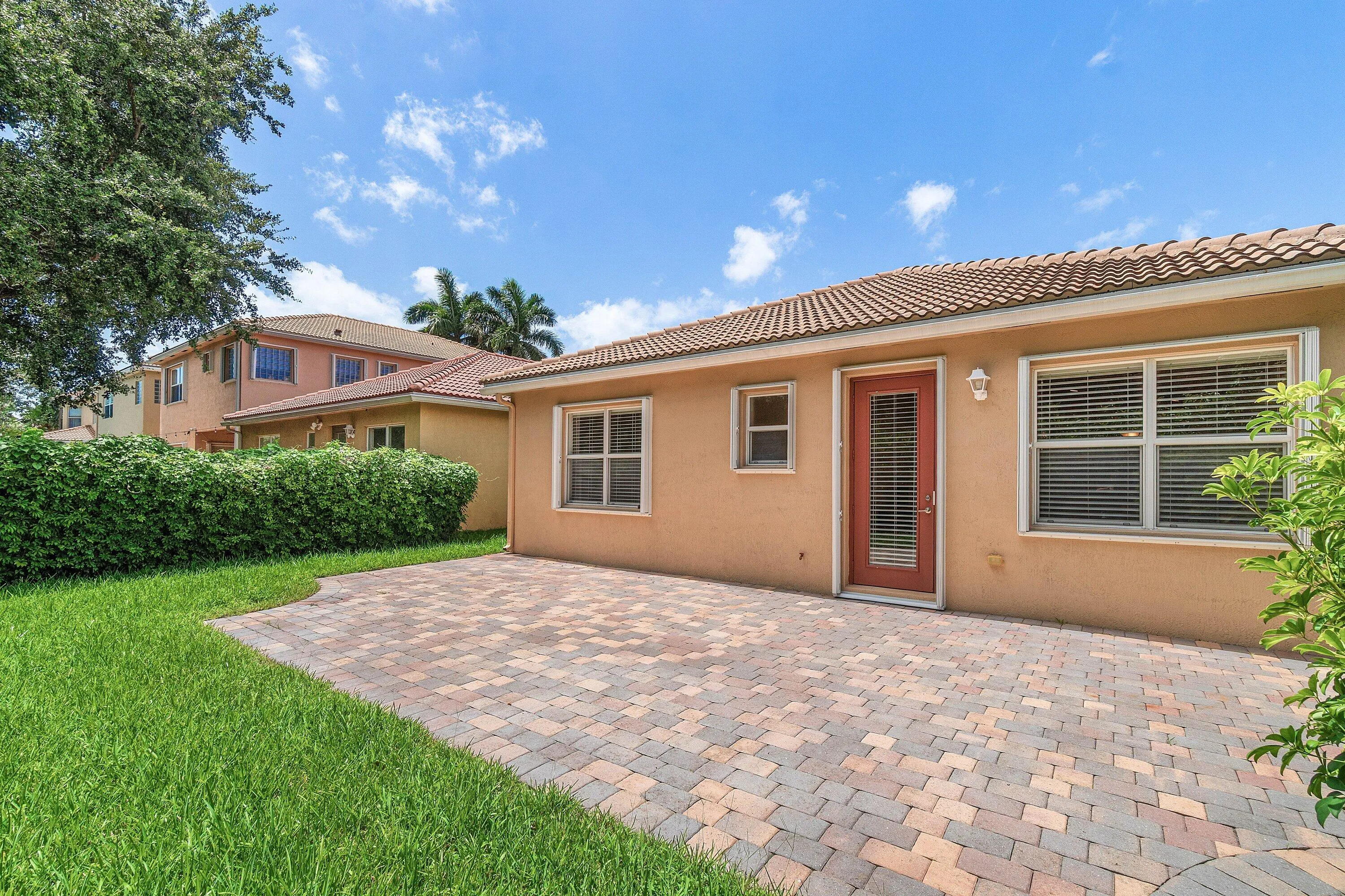 Spacious paver patio with roof tiles, and an exterior door and accordion shutters