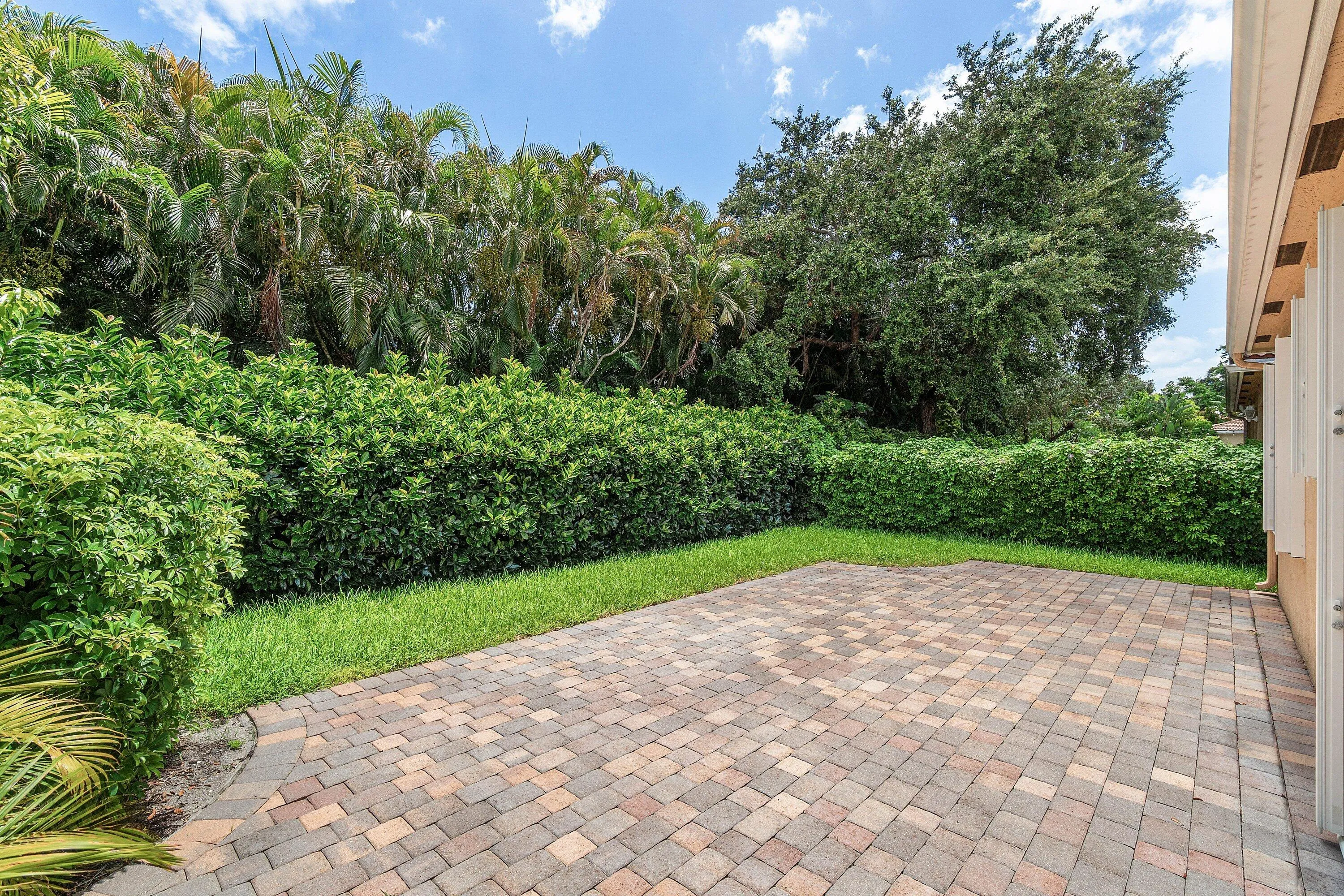 Exterior featuring a paver patio, stucco finish, tiled roof, multiple windows, and a manicured lawn