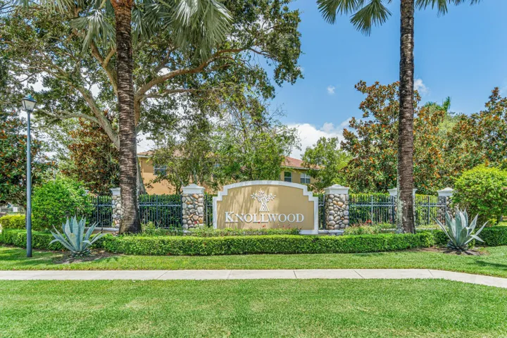 Entry monument with stone-clad pillars, wrought iron fencing, and manicured landscaping