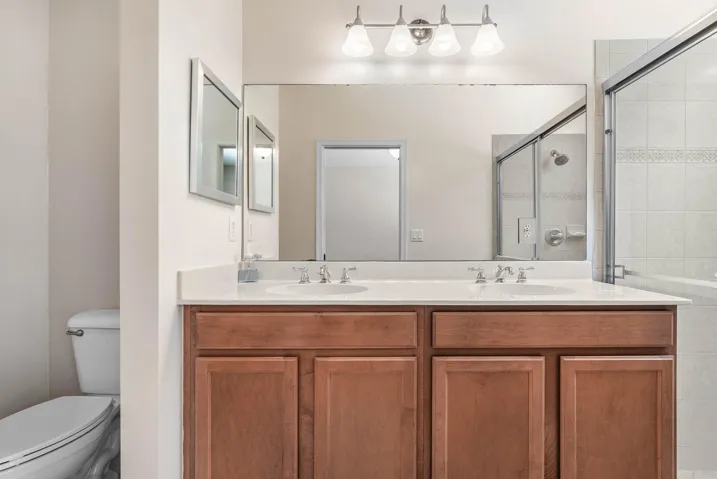 Bathroom vanity featuring dual under-mount sinks, a light-colored countertop, and wood-finish cabinetry