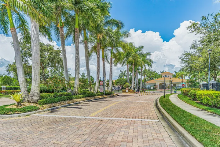 Paved brick entrance with mature palm trees and manicured landscaping