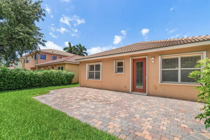 Spacious paver patio with roof tiles, and an exterior door and accordion shutters