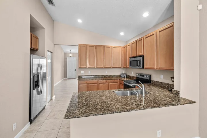 Kitchen featuring wood cabinetry, granite countertop, stainless steel appliances, and tile flooring