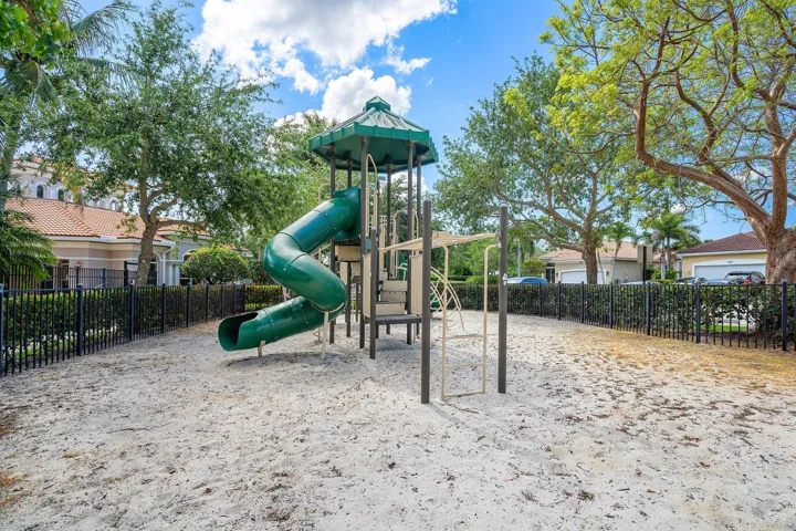 Community playground featuring a multi-level play structure with a covered tower, a curved green slide, and climbing elements