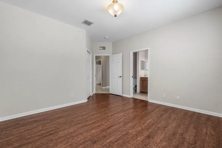 Spacious room featuring luxury vinyl flooring, light neutral wall paint, and white baseboards