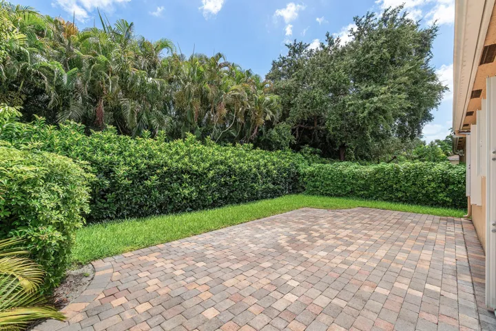 Exterior featuring a paver patio, stucco finish, tiled roof, multiple windows, and a manicured lawn