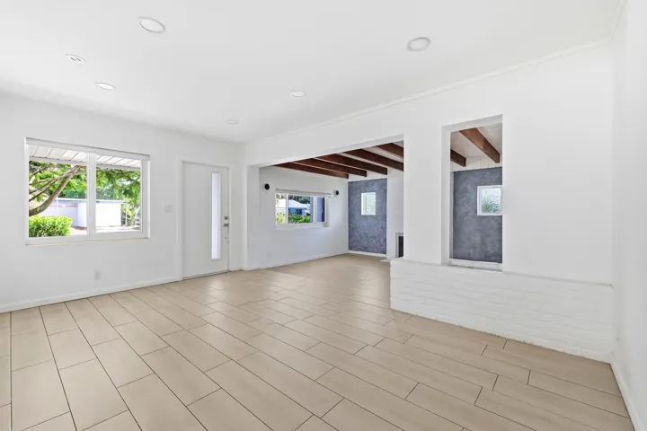 Spacious interior featuring light-toned plank tile flooring, recessed lighting, and a white entry door with a frosted glass insert