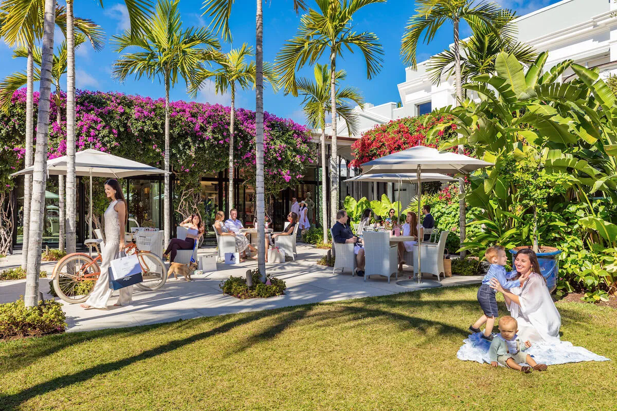 Manicured lawn with a paved patio area, surrounded by tropical foliage and palm trees