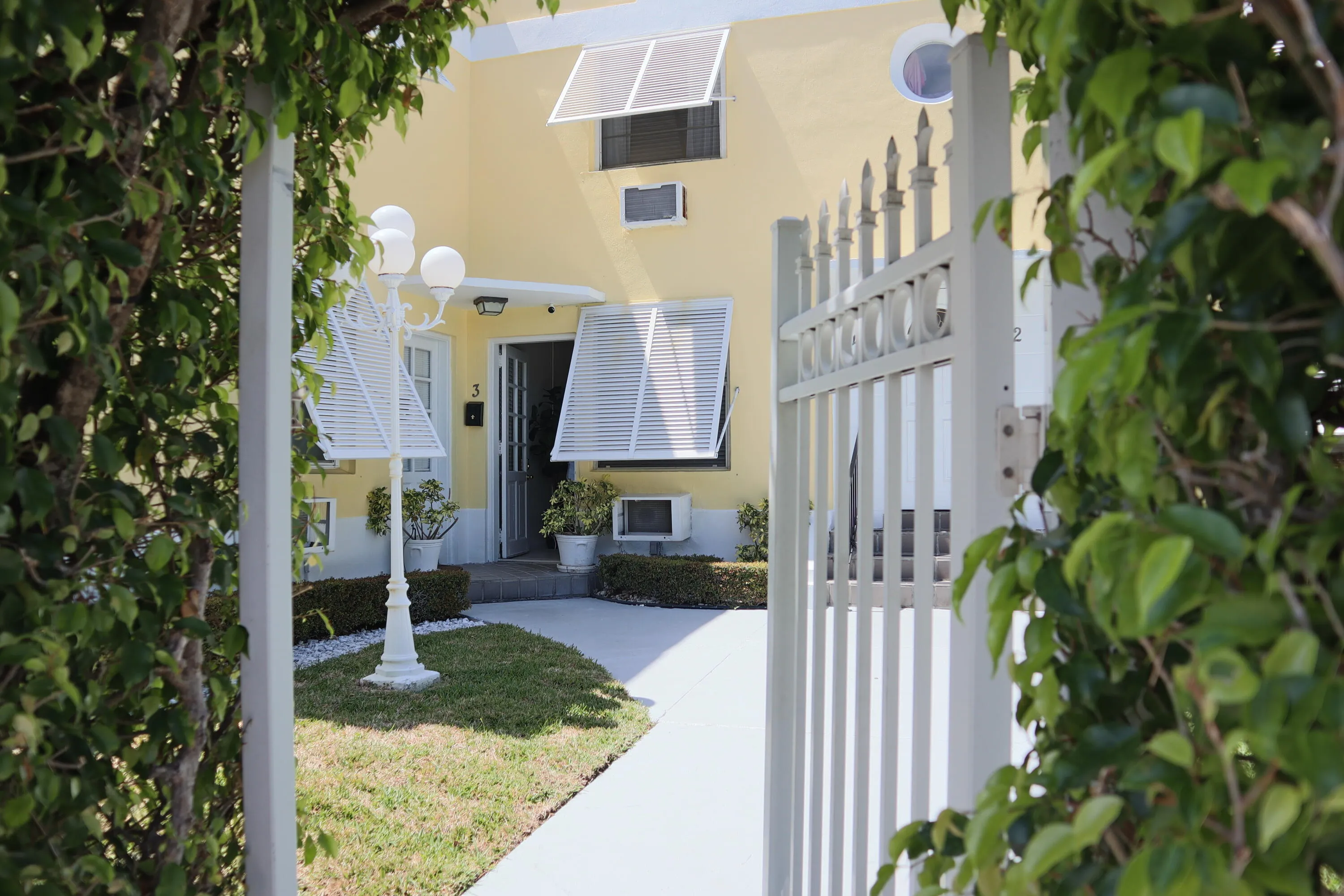 Gated entry with ornate metalwork framing a mature green archway