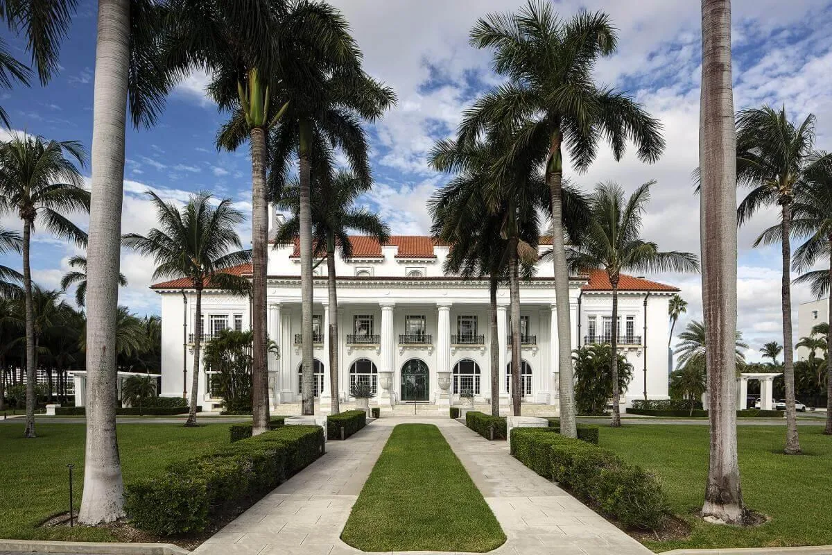 Grand Colonial-style residence featuring a prominent portico with classical columns, a red tile roof, and multiple balconies