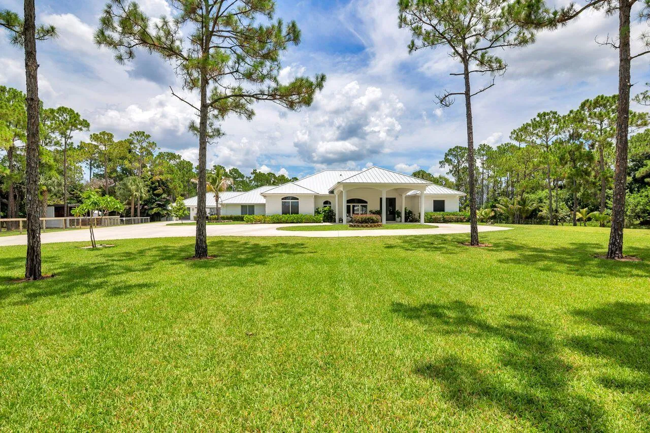 Spacious front lawn with mature trees and a circular driveway