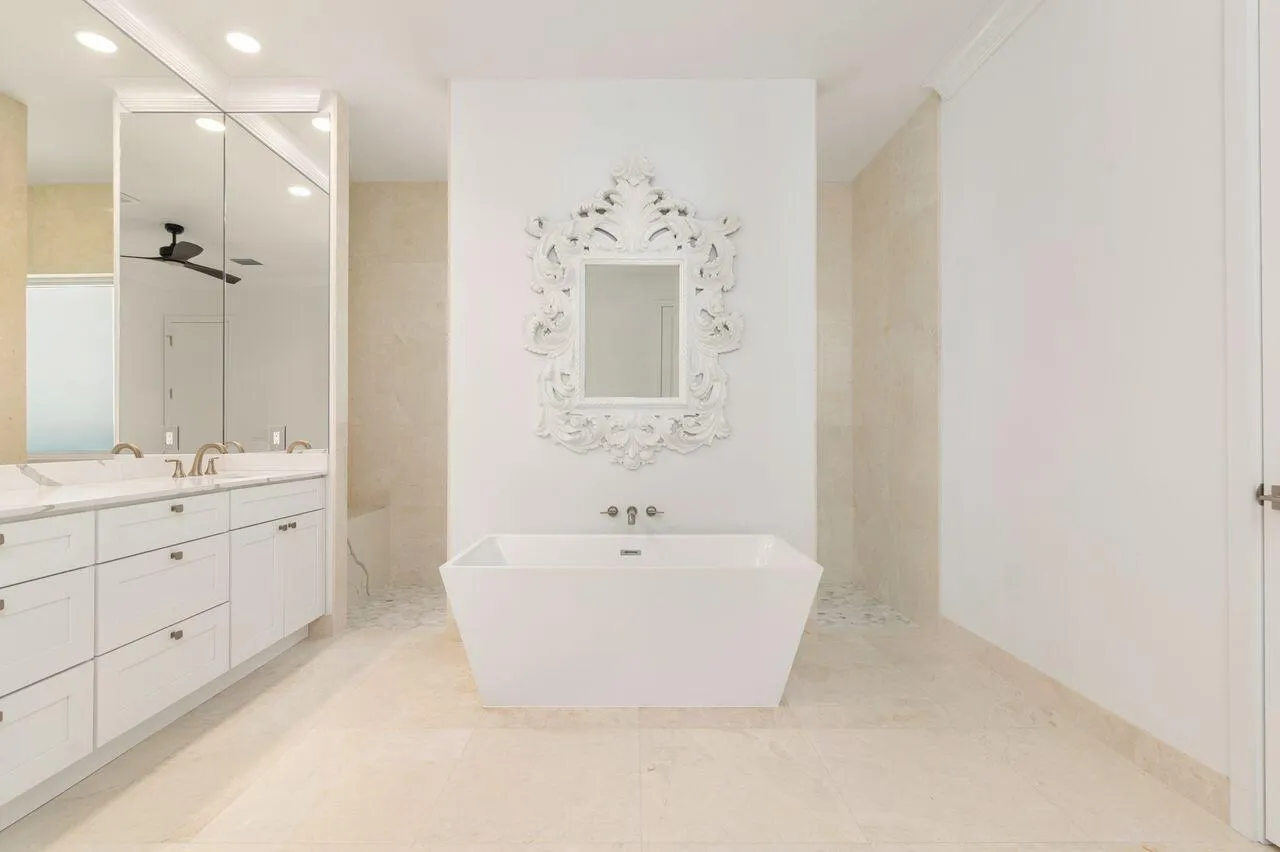 Freestanding soaking tub with a wall-mounted faucet, set against a decorative framed mirror