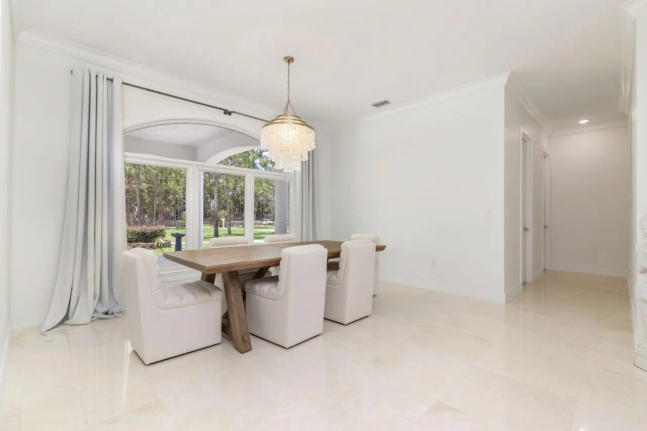 Bright interior space featuring large arched windows, crown molding, a decorative chandelier.