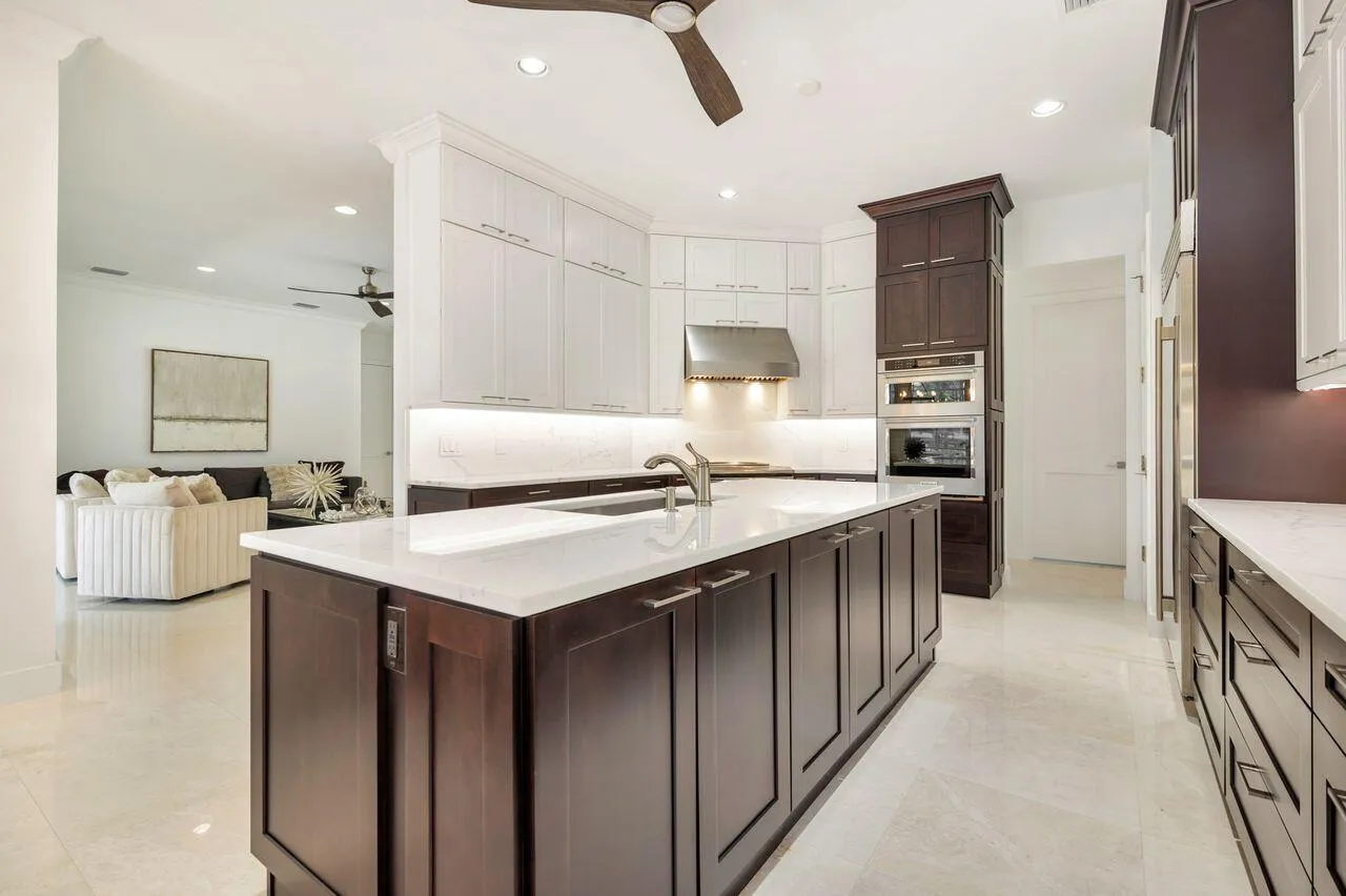 Gourmet kitchen featuring a large central island with integrated sink, two-tone cabinetry, built-in stainless steel appliances, and under-cabinet lighting