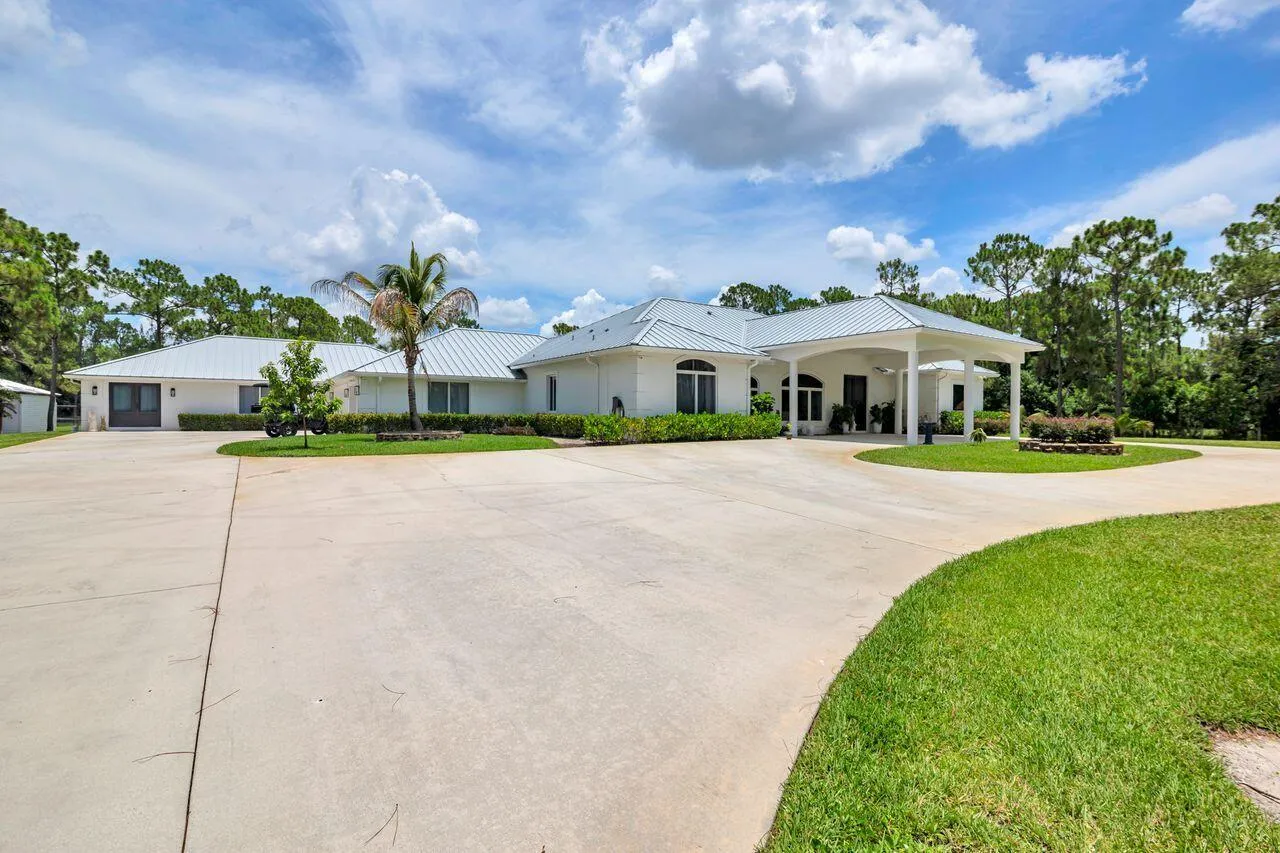 Expansive circular drive, portico, metal roof, and an attached three-car garage