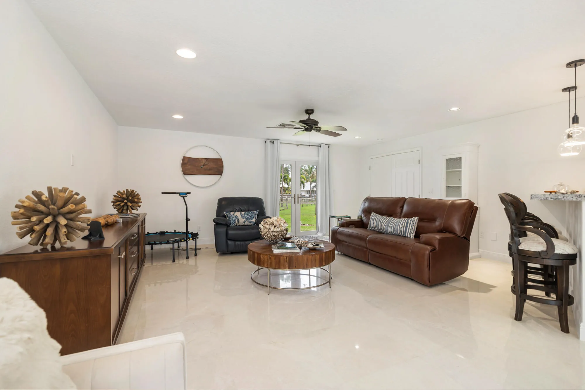 Spacious living area featuring polished marble flooring, recessed lighting, and a ceiling fan