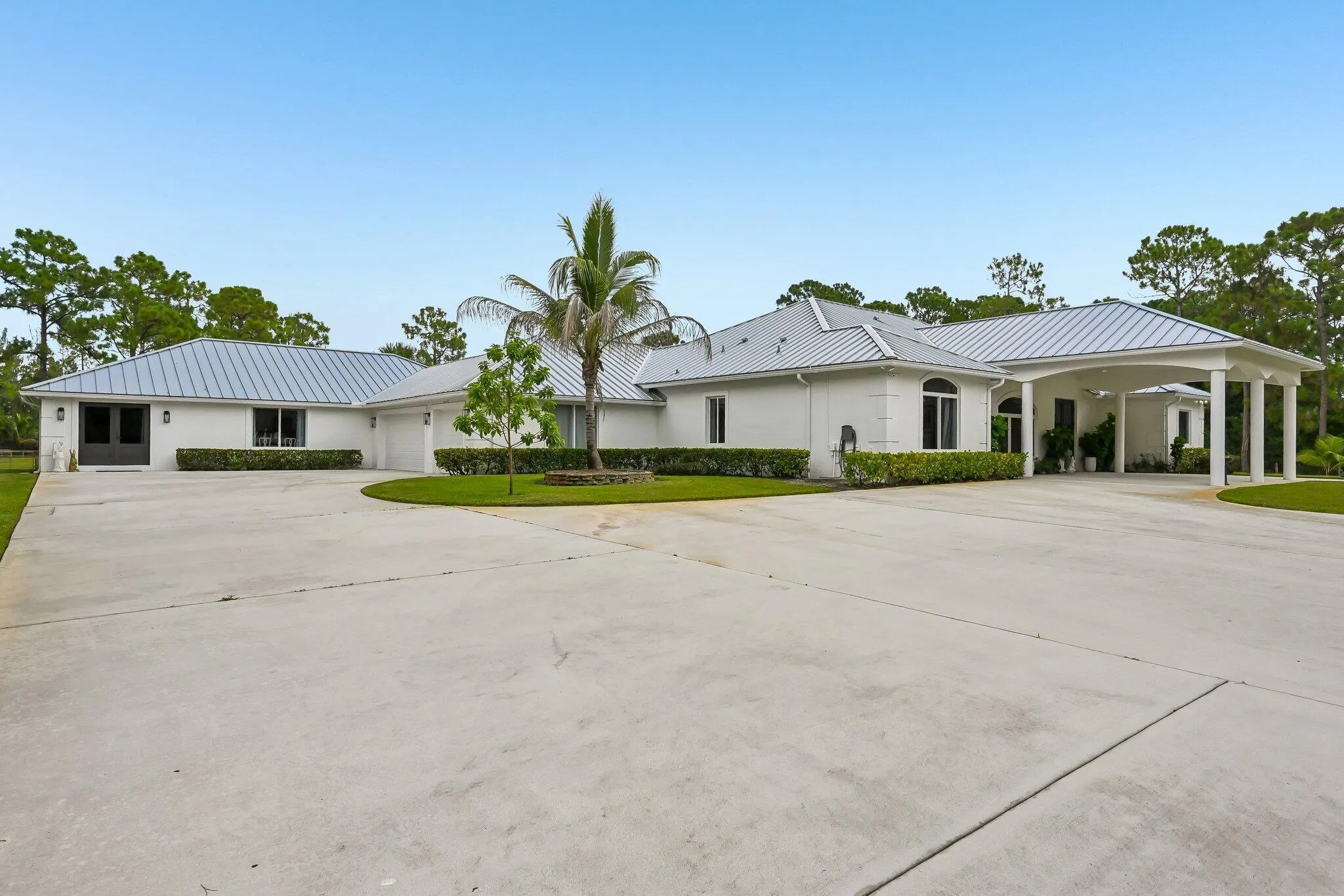 White stucco exterior with a metal roof and an arched portico entry