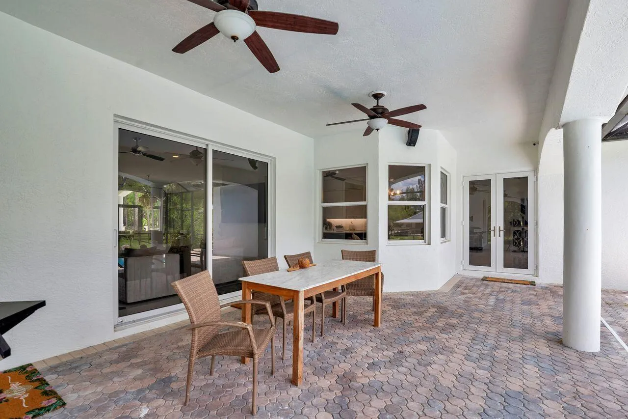Covered patio featuring paver flooring, dual ceiling fans, and multiple access points including sliding glass doors and French doors