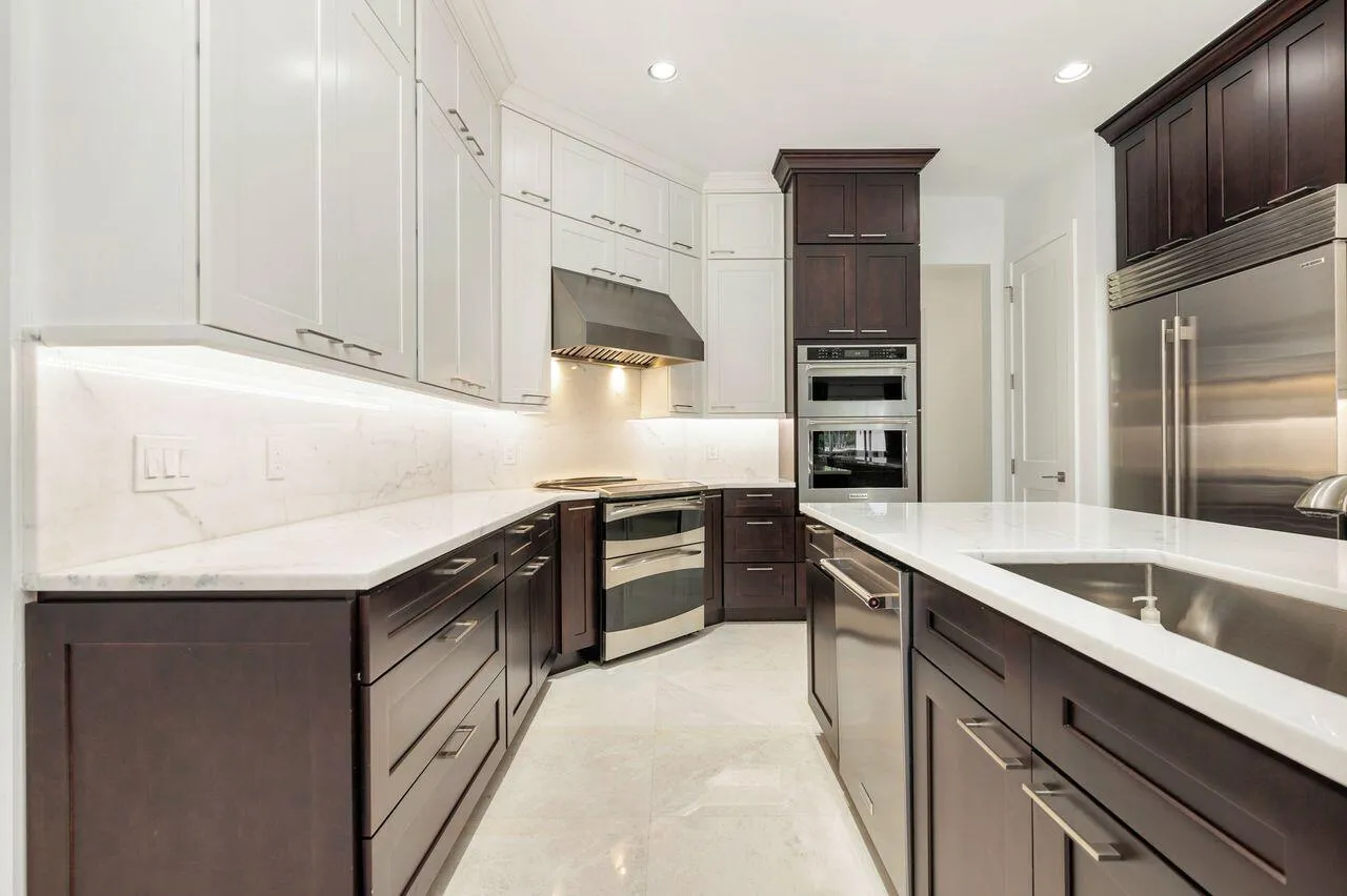 Contemporary kitchen featuring white upper cabinetry, dark wood-finish lower cabinetry, and light countertops