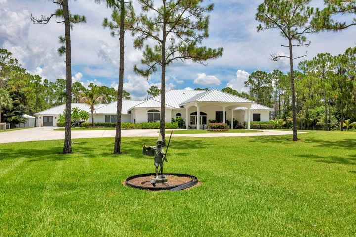 Expansive front lawn with mature trees and a circular drive