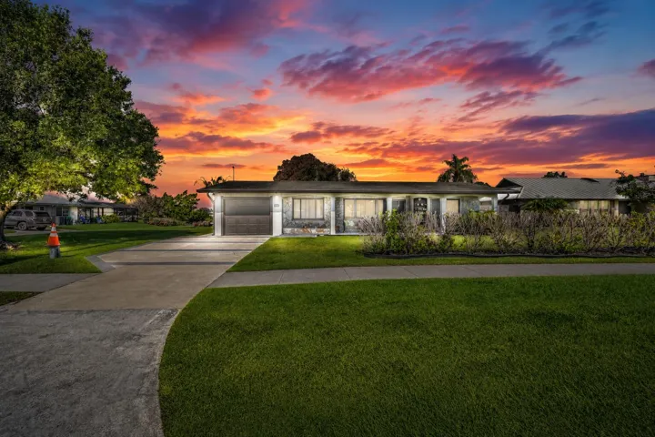 Single-story home featuring an attached garage, a paved driveway, and established landscaping