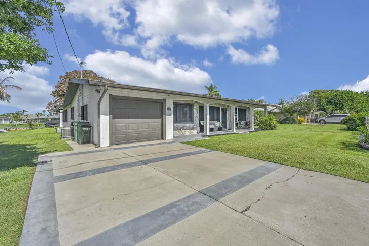 Single-story residence featuring a two-car garage, an extended driveway, and a covered front porch with columnar supports
