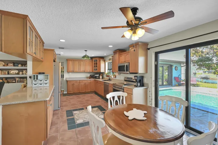 Kitchen featuring wood cabinetry, stone-finish countertops, stainless steel appliances, and tile flooring